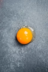 Foto op Plexiglas Close-up of the yolk of a chicken egg. On a gray stone background. Top view. © Yaruniv-Studio