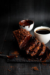 
Chocolate cake with cocoa powder and a cup of coffee. black background. dessert
