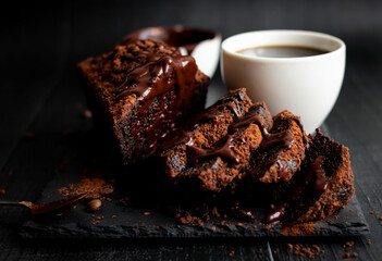 
Chocolate cake with cocoa powder and a cup of coffee. black background. dessert