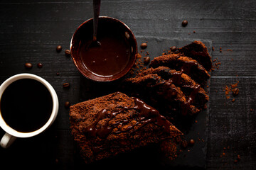 
Chocolate cake with cocoa powder and a cup of coffee. black background. dessert