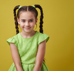 A young girl in green dress is smiling for the camera. The image has a bright and cheerful mood, with the girl's smile and the green dress adding to the overall positive atmosphere