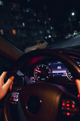 Driver's hands on the steering wheel of a car at night, night driving.