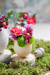 Florist at work: woman shows how to make simple Easter decoration with egg shell and various flowers.