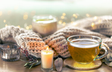 Glass cup of herbal tea, candles and knitted element.