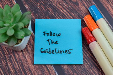 Concept of Follow the Guidelines write on sticky notes isolated on Wooden Table.