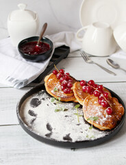 Pancakes with red currants and jam. on a black plate. dessert