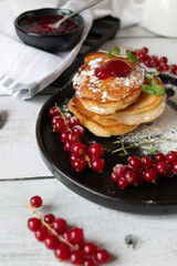 Pancakes with red currants and jam. on a black plate. dessert