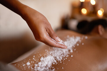 Hand, massage and salt with woman at spa on bed or table for luxury pamper treatment closeup....