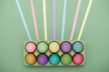 Green carton of painted eggs with leading lines. Geometric Easter background
