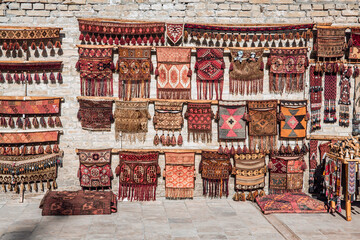 Street shop in Bukhara showcases a wall adorned with traditional Uzbek rugs and textiles, a testament to the enduring craftsmanship - obrazy, fototapety, plakaty