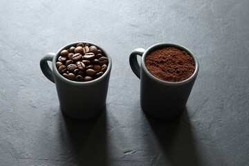 Due tazze di caffè grigie con chicchi di caffè e caffè macinato isolati su sfondo grigio. Vista...