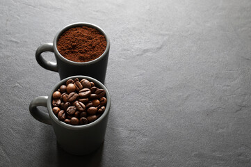 Naklejka premium Due tazze di caffè grigie con chicchi di caffè e caffè macinato isolati su sfondo grigio. Vista dall'alto. Copia spazio.
