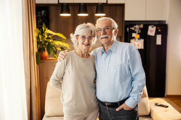 Portrait of a happy senior couple standing at home and smiling at the camera.