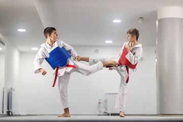 Taekwondo athletes in doboks are practicing combat and kicking at martial art class at school.