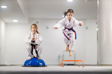 Taekwondo girls practicing balance at martial arts school class.