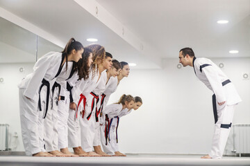Taekwondo kids are bowing to their coach at martial art school.