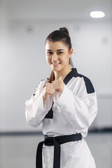 Portrait of a taekwondo girl in strike position standing at martial art school.