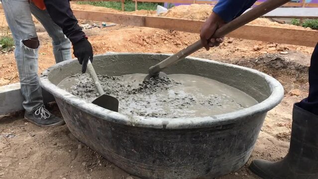 Young man is mixing concrete in the traditional way, Mixing together to make a strong concrete floor, Mixing concrete concept, Slow motion