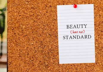 Paper pinned on board with text written BEAUTY (HAS NO) STANDARD, concept of rebel against standard...