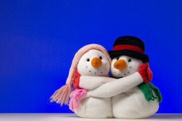 Hugging snowmen couple on blue background