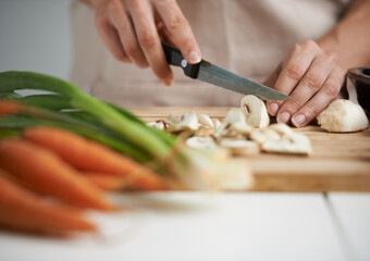 Cooking, food and hands with vegetables in kitchen on wooden board for cutting, meal prep and...