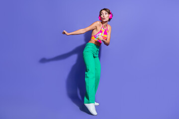 Full body size photo of young lady thin body wear crop top and pants dance with headphones look novelty isolated on purple color background