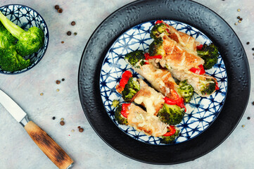 Meat rolls with broccoli and pepper on a plate.