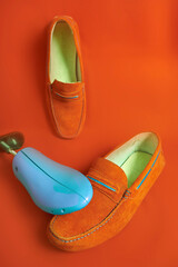 Blue device for stretching shoes and orange men's moccasins