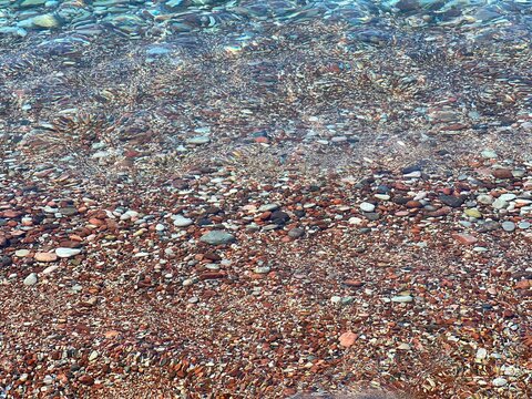 Sea clear water and colorful pebbles stones in the beach.
