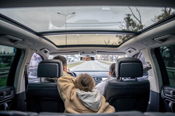 Rear view. Little girl sitting in back seat of car during family trip.