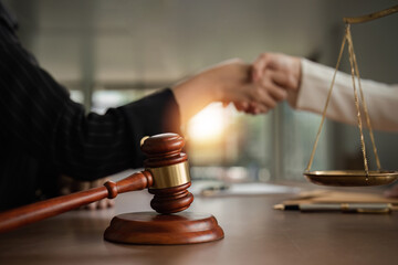 A lawyer and a businesswoman shake hands and reach an agreement on a cooperation contract document....