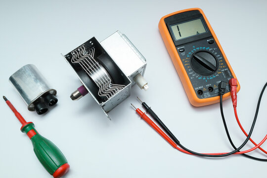 New magnetron and capacitor spare parts for microwave oven with multimeter.