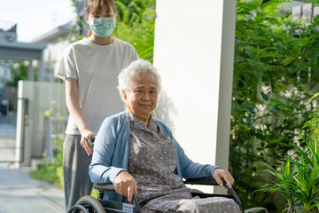 Caregiver help and care Asian senior woman patient sitting on wheelchair to ramp in nursing...