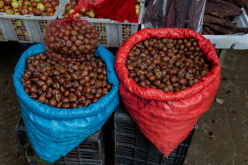 Fresh chestnuts in large plastic sacks at an open air market in Vietnam.
