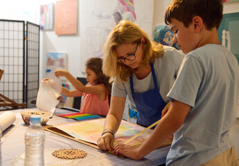 Caucasian middle aged woman educator works with children, teaching art in the development center....