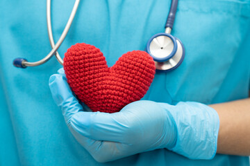 Doctor holding a red heart in hospital ward, healthy strong medical concept.