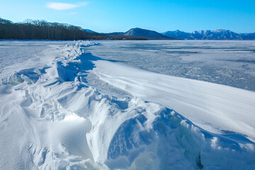 Fototapeta na wymiar 氷に覆われた冬の湖の巨大な氷の亀裂。日本ではおみわたりと呼ばれる氷丘脈の自然現象。北海道の屈斜路湖。