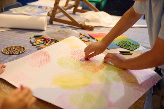 Close-up view schoolkids drawing with pastel color pencils, creating a background for further artwork during art class