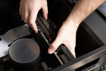 Computer engineer assembling PC, hand holding video card, hardware installation.