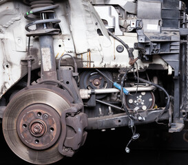 Fototapeta premium The front part of the car after an accident in a car repair service with a disassembled hood and metal grille and various parts in the garage box.