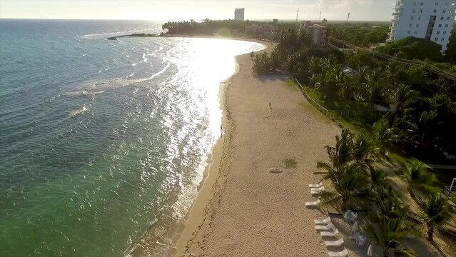 Drone panning from the right to the left side of the frame above the beachfront of Miami Beach, a popular getaway located in Central Greece.