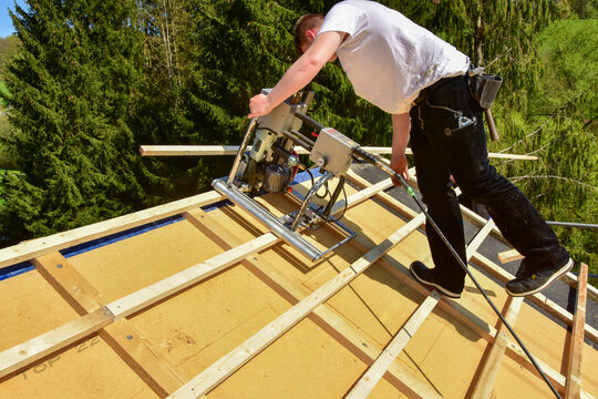 Die Dachlatten eines Steildachs werden vom Dachdecker mit dem Einlattgerät / Einlattblitz mit Kappsäge halbautomatisch verlegt