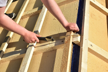 Dachdecker beim Verlegen und befestigen der Dachlatten eines Steildachs auf der Holzfaserdämmung für die Eindeckung mit Ziegeln - obrazy, fototapety, plakaty