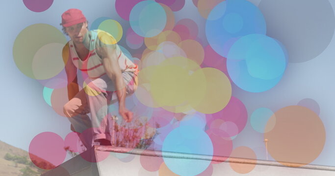 Image of colourful spots over caucasian man skateboarding