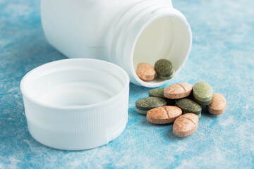 Multicolored medical pills, drugs or tablets for treatment on blue background, vitamins and...