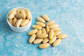 Yellow medical pills, drugs or tablets for treatment on blue background, vitamins and minerals, nutritional or dietary supplement