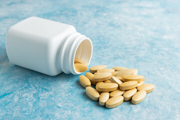 Yellow medical pills, drugs or tablets for treatment on blue background, vitamins and minerals,...