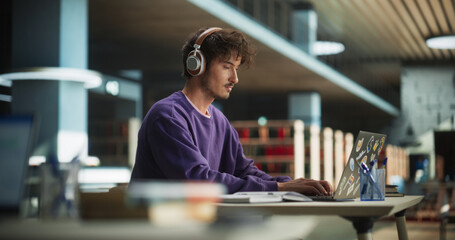 Thoughtful College Student Using Laptop Computer to Study in a Modern Library. Handsome Smart Man...