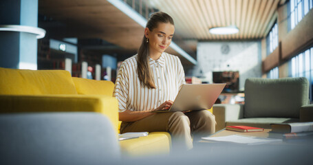 Smart College Student Using Laptop Computer to Study in a Public Library. Beautiful Young Woman...