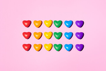 colorful heart-shaped candies show lgbtq pride rainbow flag isolated on pink background, peace and...